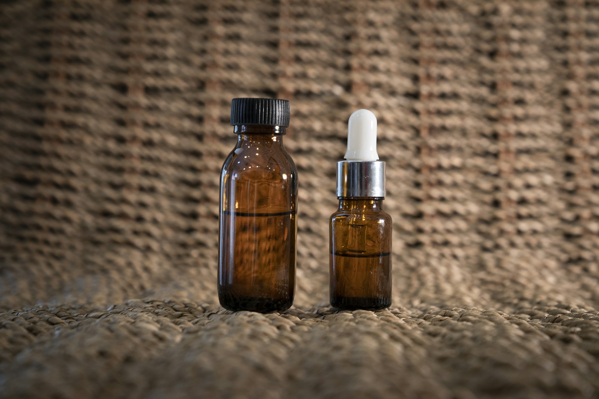 Two amber bottles of massage oil on woven linen